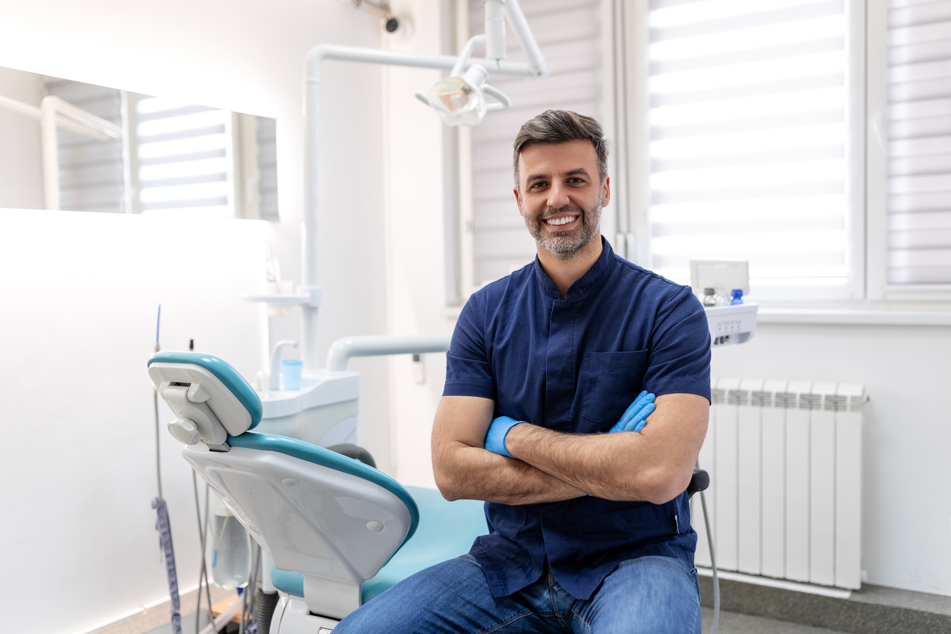 Dentist man smiling while standing in dental clinic. Portrait of confident a young dentist working in his consulting room